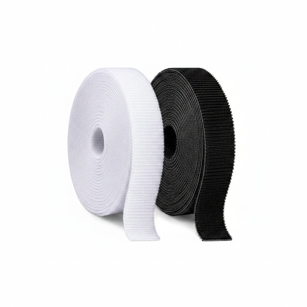 Two rolls of velcro tie, one white and one black, on a white background.