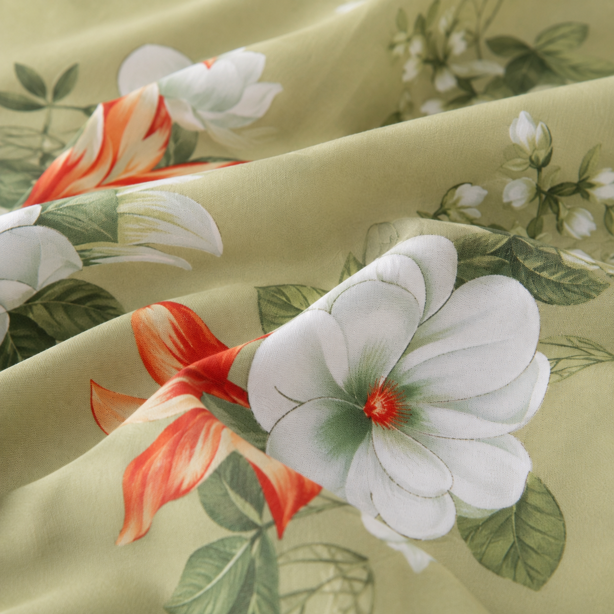 A close-up of draped fabric featuring a floral print with large white flowers, green leaves, and orange-red accents on a pale yellow-green background.