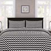 Bed with black and white zigzag patterned bedding in a bedroom setting.