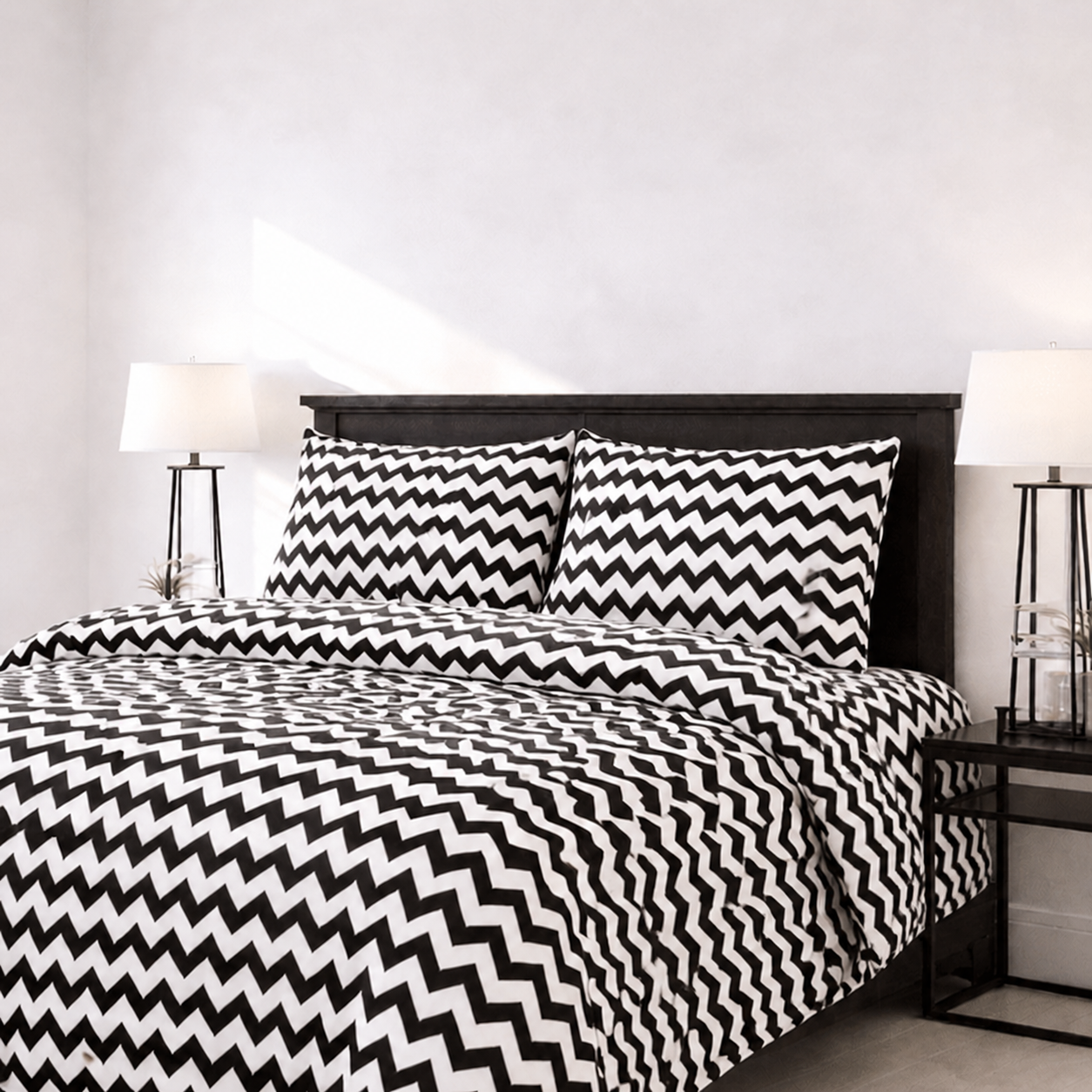 Bed with black and white zigzag patterned bedding in a bedroom setting.