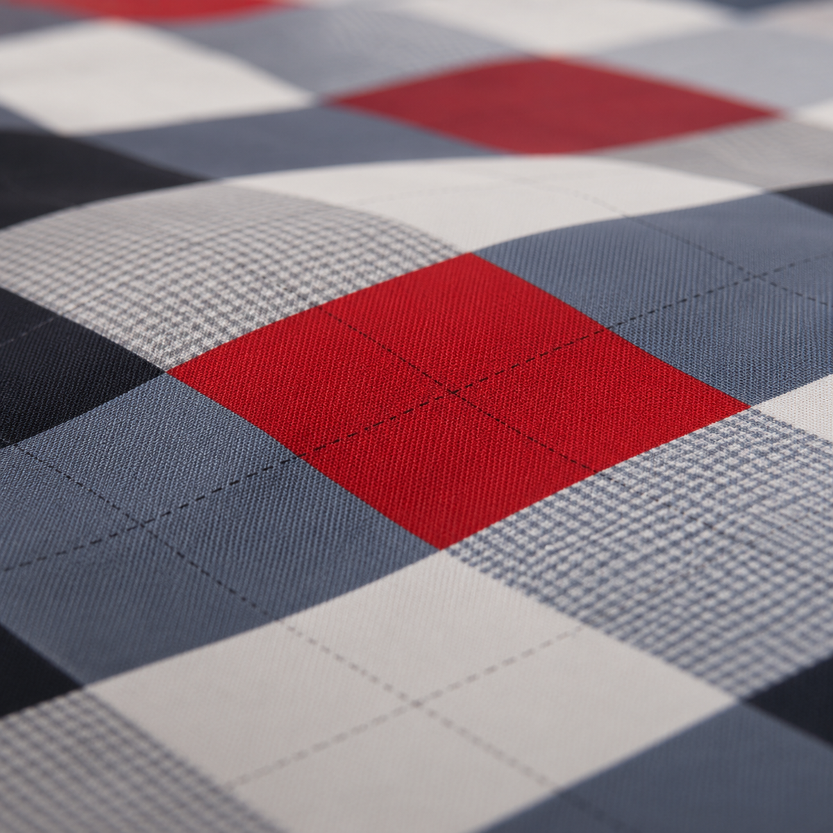Close-up of a plaid fabric pattern with red, white, navy, and gray blocks, showing the woven texture and stitched grid lines.