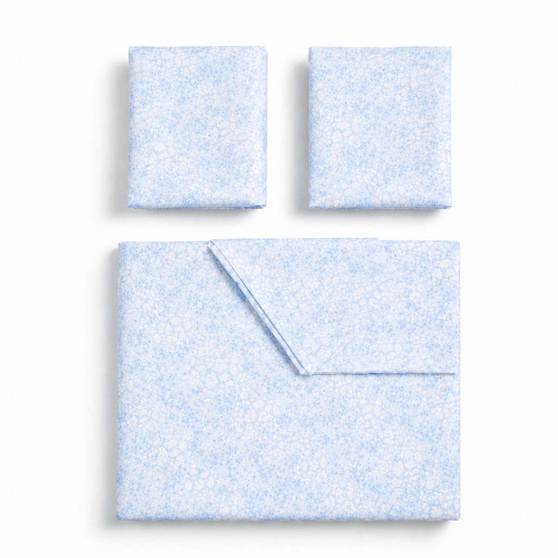 A light blue and white speckled fabric bedding set, including a flat sheet and two matching pillowcases, arranged neatly on a clean white background.