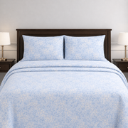 Blue floral patterned bedding set on a bed with matching pillows.
