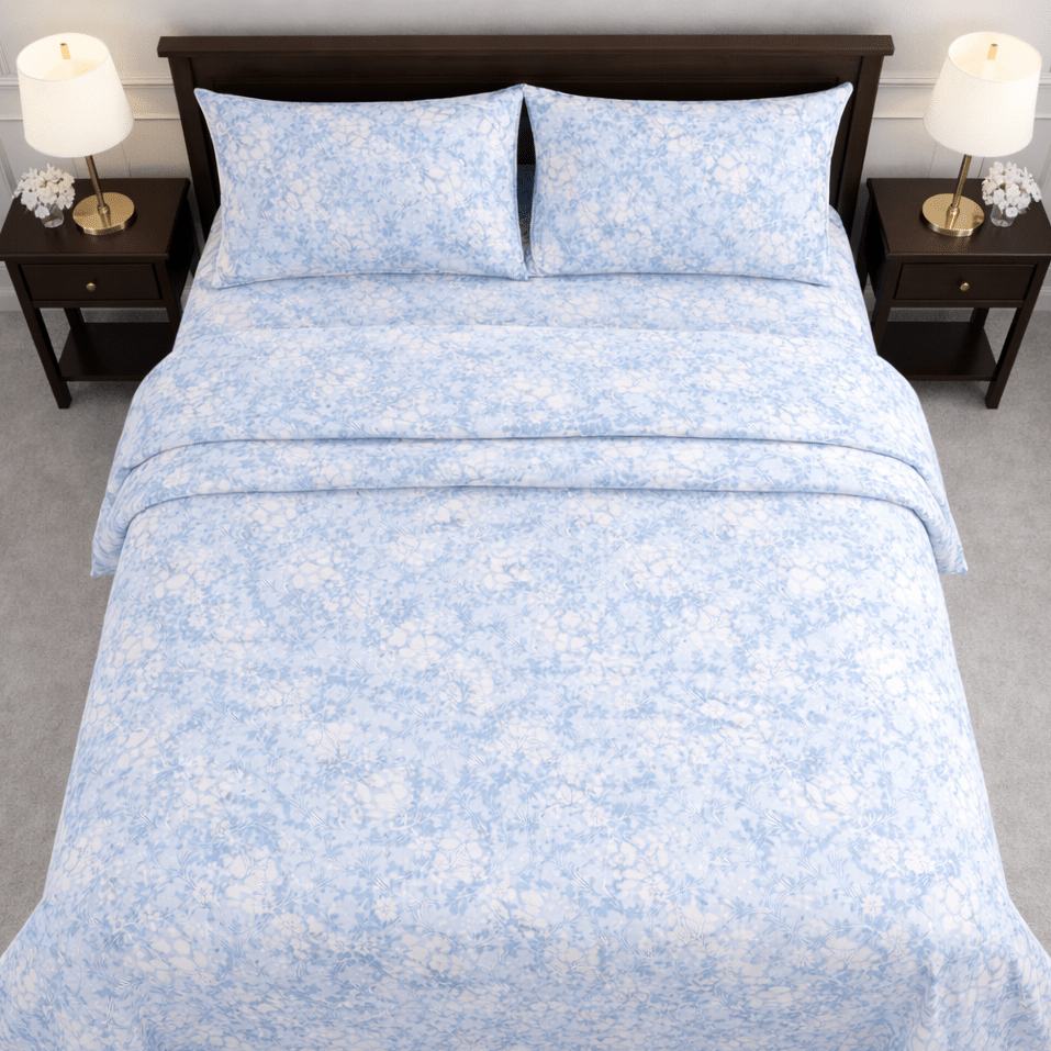 Blue floral patterned bedding set on a bed with matching pillows, flanked by two nightstands with lamps.