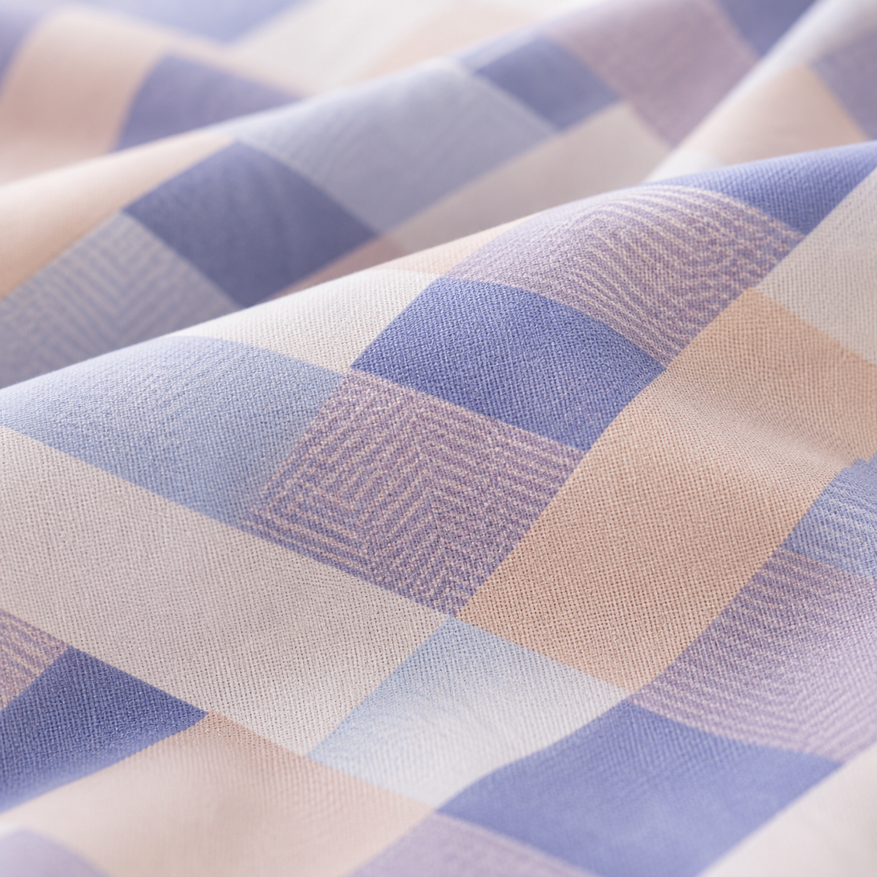 A close-up of draped fabric with a soft plaid pattern in dusty blue, lavender, and warm beige tones.