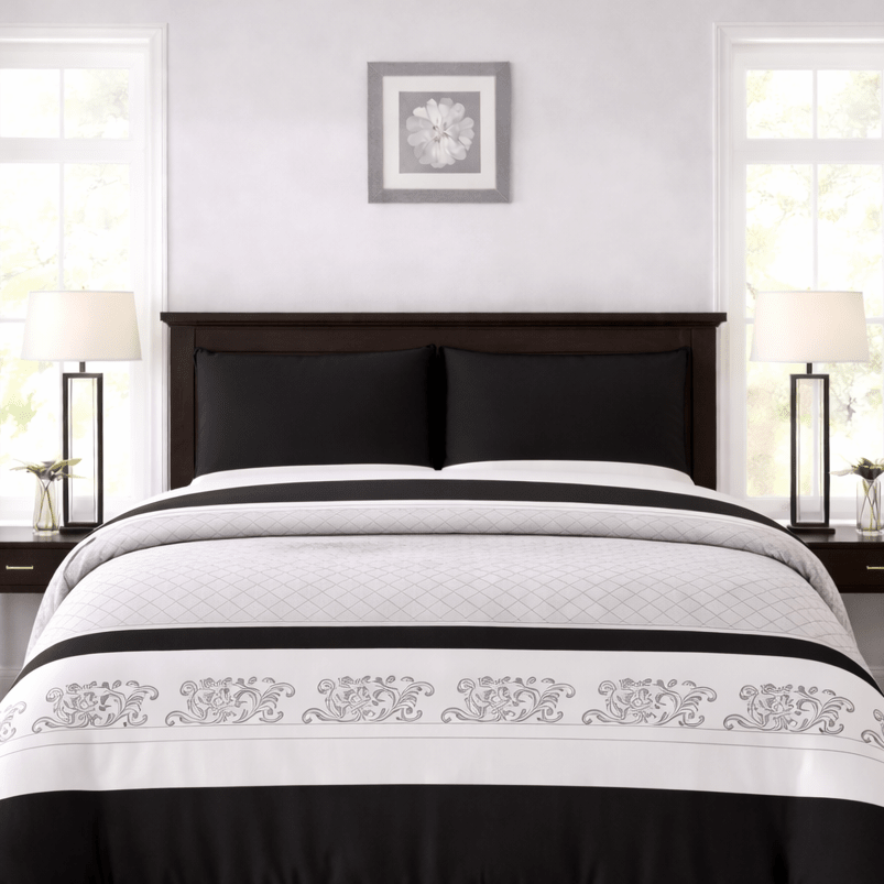 Black and white bedspread set on a bed in a bedroom with side tables and lamps.