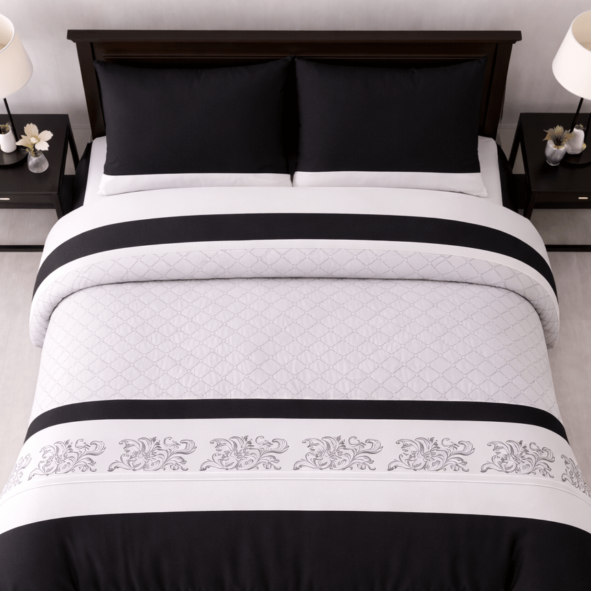 Black and white quilted bedspread with decorative patterns on a bed in a bedroom setting.