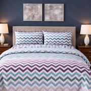 Bedroom with a bed featuring a chevron patterned comforter, two nightstands with lamps, and framed artwork on the wall.
