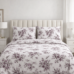 Floral patterned comforter set on a bed in a bedroom setting with nightstands and lamps.