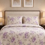 Floral bedding set on a bed in a bedroom with lamps and artwork.