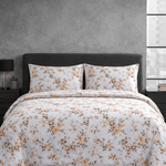 Floral patterned comforter set on a bed in a bedroom setting with nightstands and a lamp.