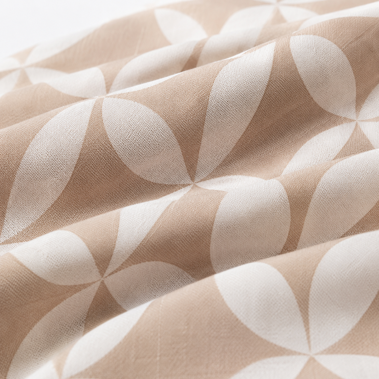 A close-up of draped fabric with a repeating geometric leaf pattern in warm beige and off-white.