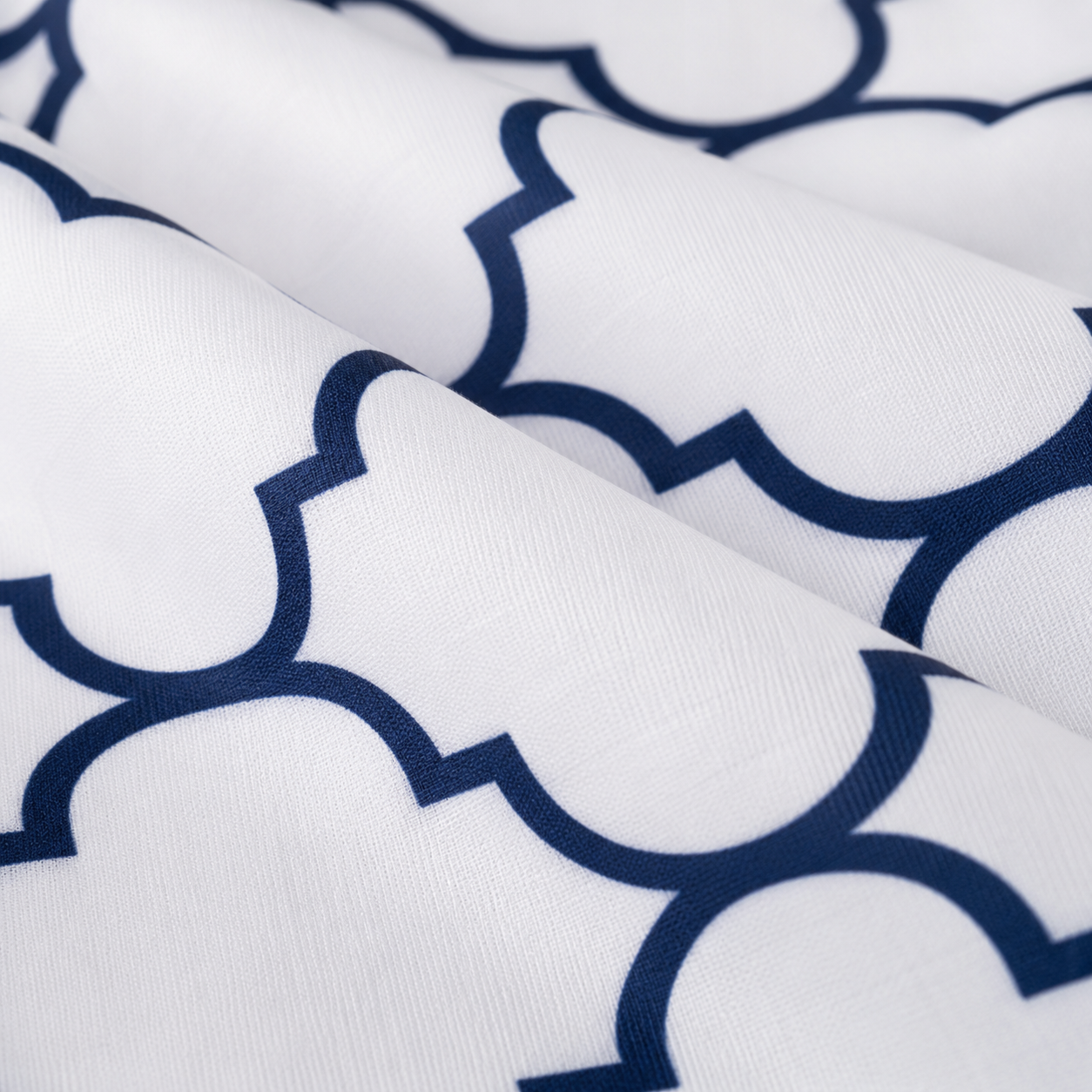 White fabric with a navy blue geometric trellis pattern, shown in a close-up with soft folds.