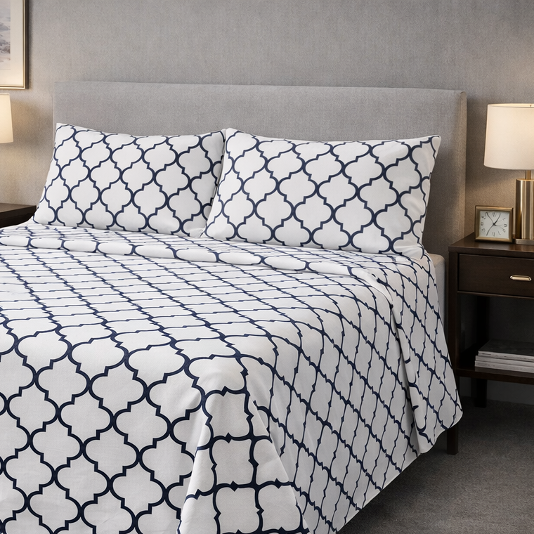 Bed with white and navy geometric patterned bedding in a bedroom setting.