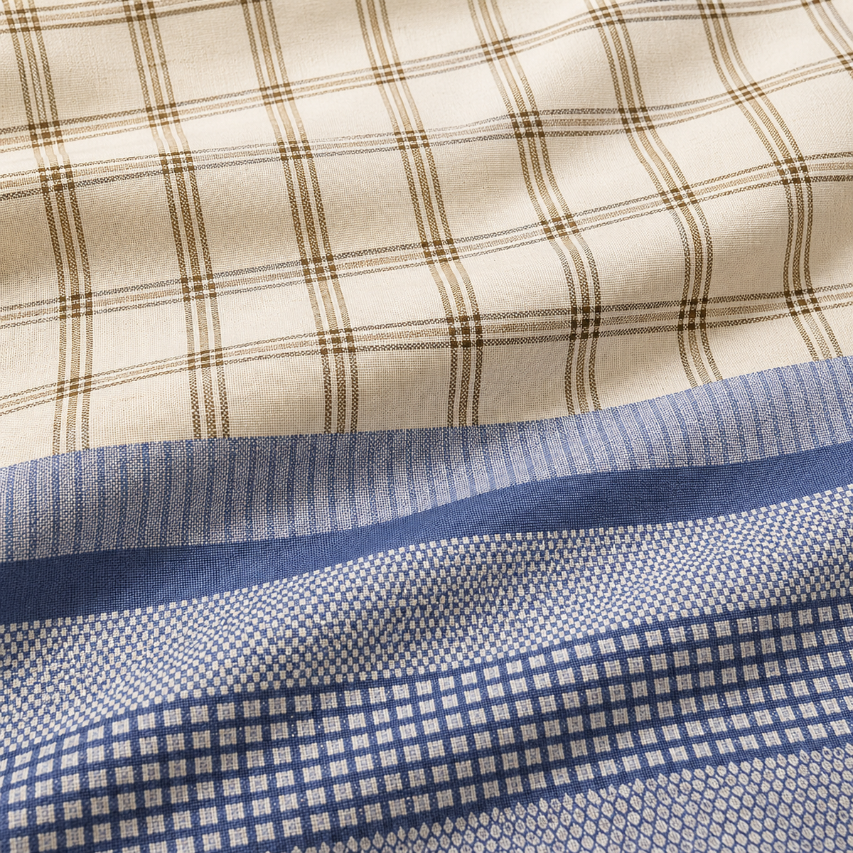 Bed with plaid bedding and pillows against a brick wall.