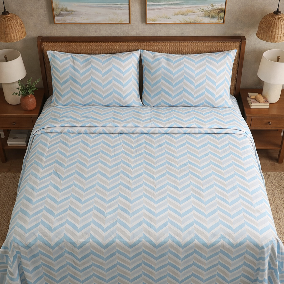 Bed with blue and white chevron patterned bedding in a bedroom setting.