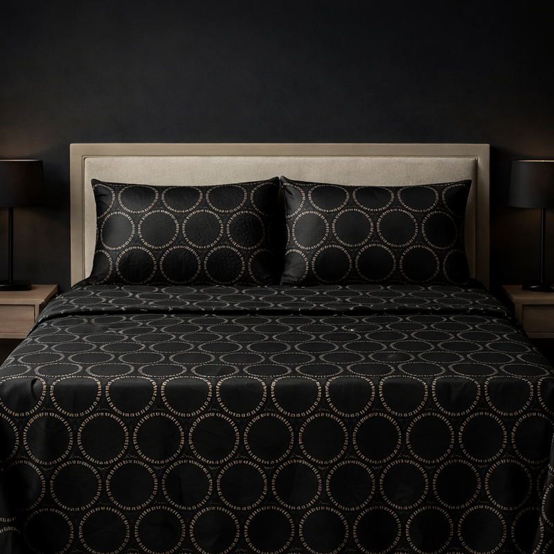 Bed with black patterned bedding in a dimly lit room