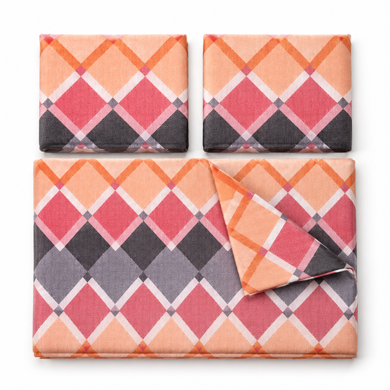 Three square fabric items with a geometric diamond plaid pattern in coral, pink, orange, gray, and black, arranged on a white background. Two are shown flat, and one is folded over the bottom right.