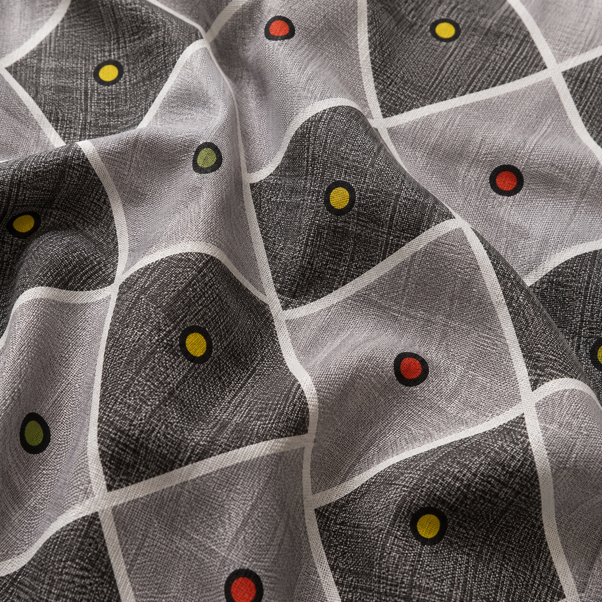 A close-up of a patterned fabric with a gray and white geometric grid design accented by small colored dots in yellow, red, and green.