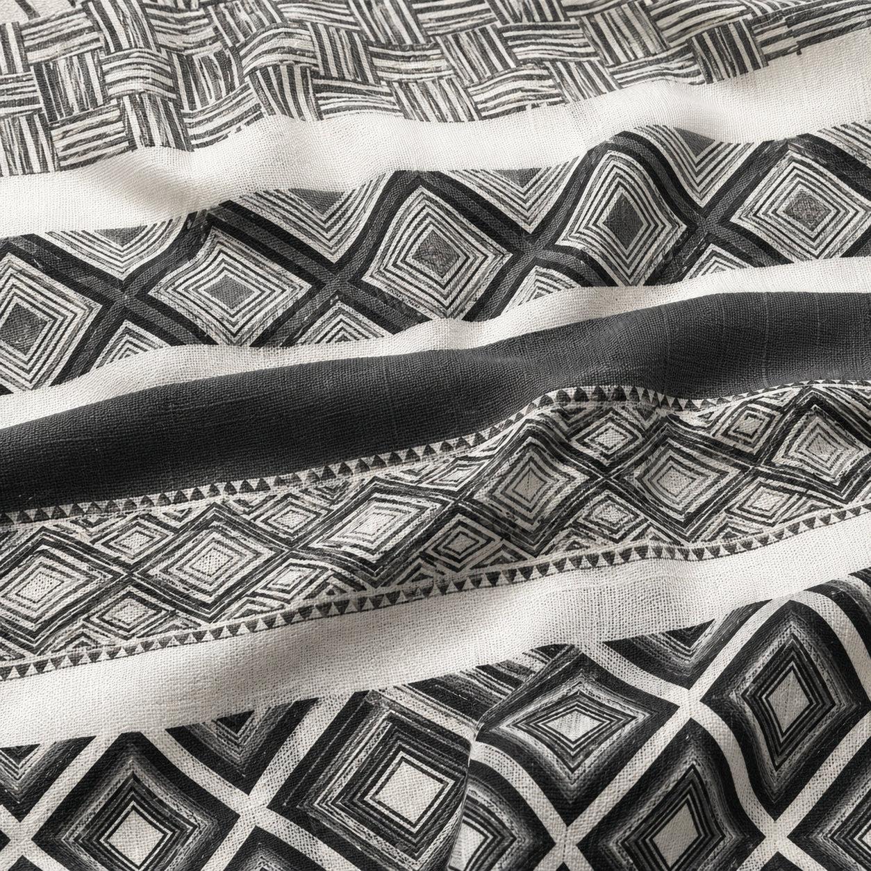 A close-up of a black and off-white patterned fabric with geometric diamond and basketweave motifs, draped to show texture and folds.