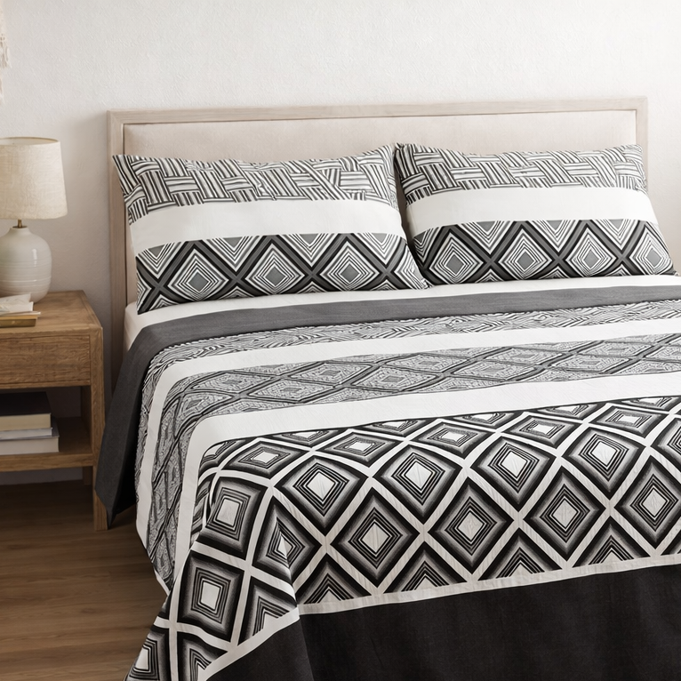 Bed with black and white geometric patterned bedding in a bedroom setting.